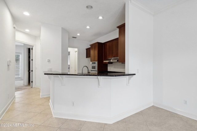 kitchen with kitchen peninsula, white oven, sink, and a breakfast bar area