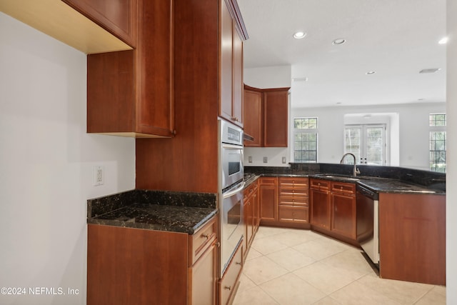 kitchen with dark stone countertops, light tile patterned flooring, sink, and stainless steel dishwasher