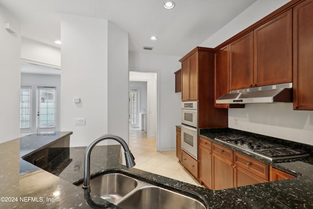 kitchen featuring light tile patterned floors, sink, stainless steel gas cooktop, dark stone counters, and white double oven