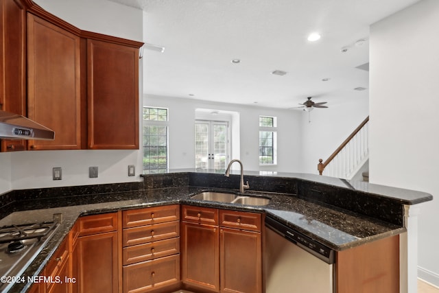 kitchen with kitchen peninsula, dark stone counters, sink, appliances with stainless steel finishes, and ceiling fan