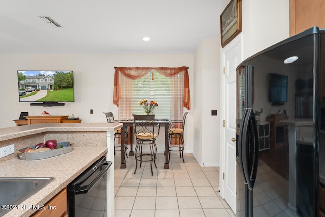 kitchen with black appliances, sink, and light tile patterned floors