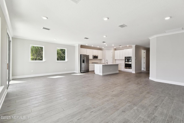 75582 Banyan Way, Yulee, FL 32097 - unfurnished living room featuring crown molding, baseboards, light wood finished floors, recessed lighting, and a sink
