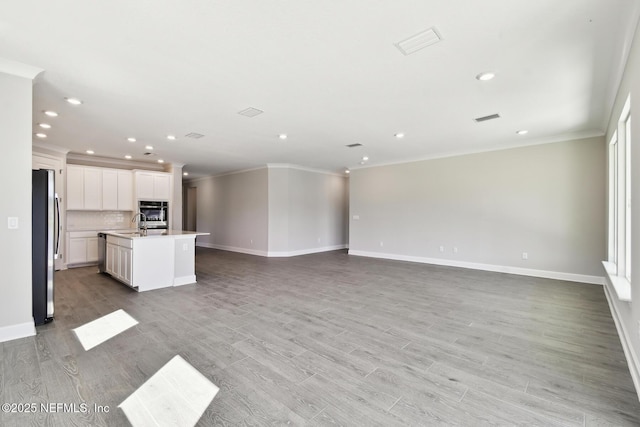 75582 Banyan Way, Yulee, FL 32097 - unfurnished living room featuring ornamental molding, recessed lighting, baseboards, light wood-style flooring, and a sink