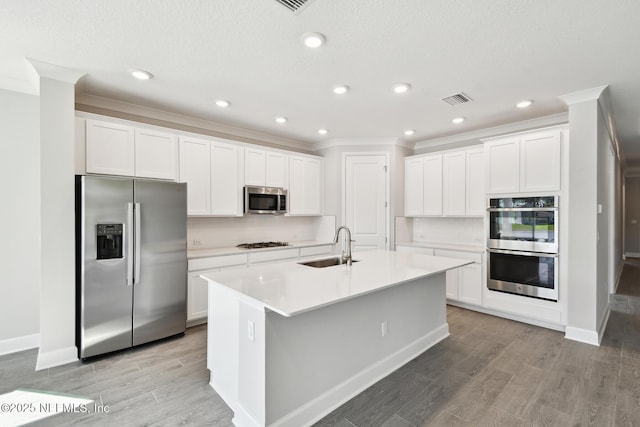 75582 Banyan Way, Yulee, FL 32097 - kitchen featuring appliances with stainless steel finishes, a sink, light wood-style floors, ornamental molding, and white cabinetry
