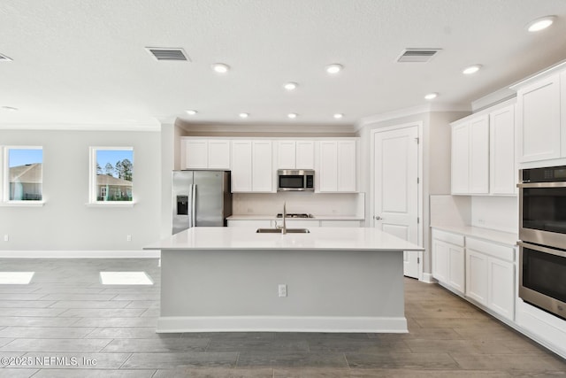 75582 Banyan Way, Yulee, FL 32097 - kitchen featuring stainless steel appliances, ornamental molding, a center island with sink, wood finished floors, and light countertops
