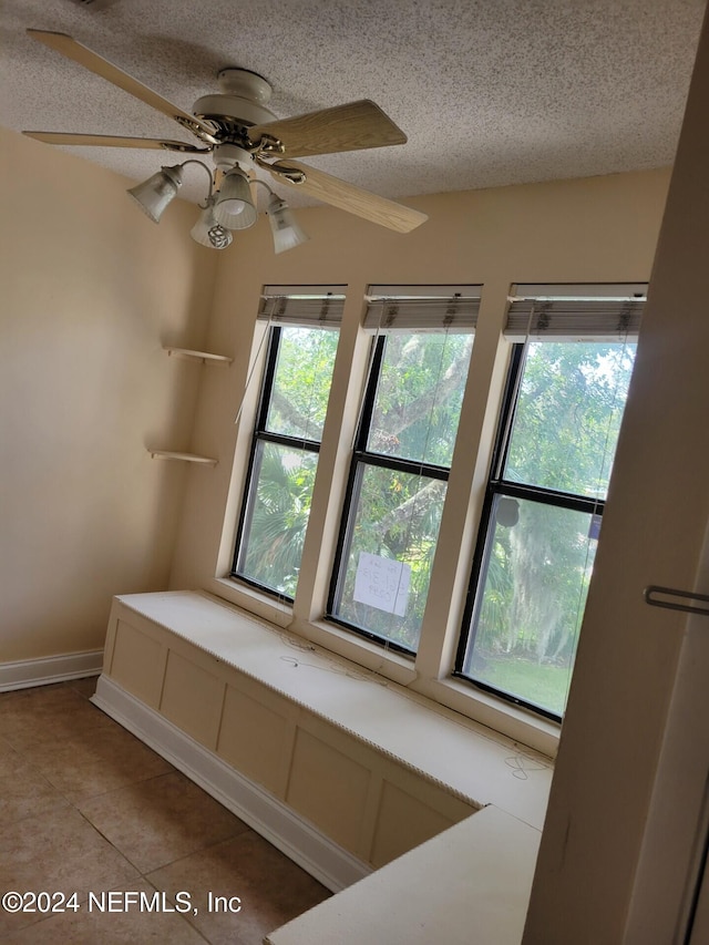 interior space featuring ceiling fan, light tile patterned flooring, a textured ceiling, and a wealth of natural light