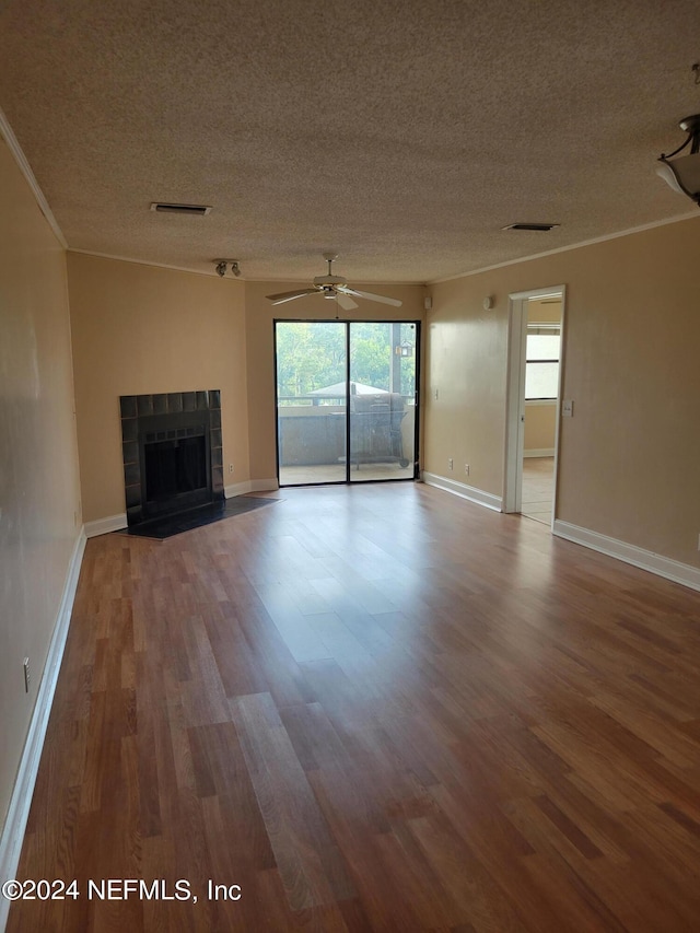 unfurnished living room with a wealth of natural light, wood-type flooring, a tile fireplace, and ceiling fan