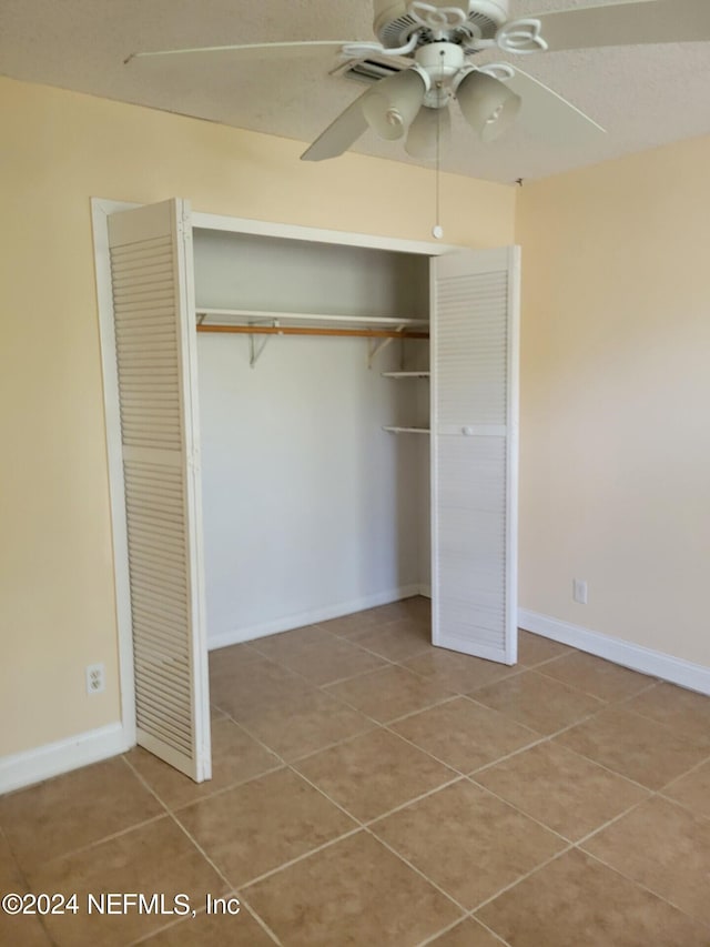 unfurnished bedroom featuring a closet, ceiling fan, and tile patterned floors