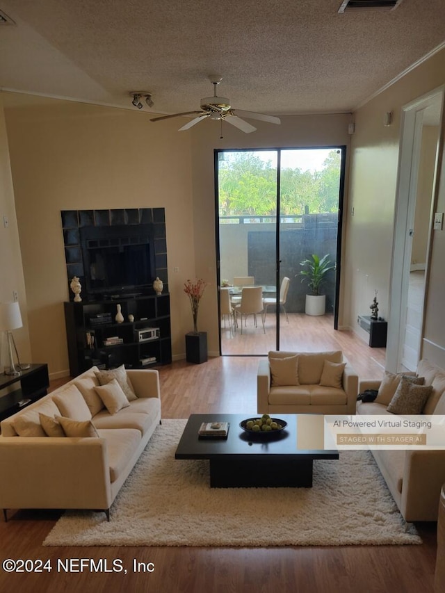 living room with ceiling fan, wood-type flooring, and a textured ceiling