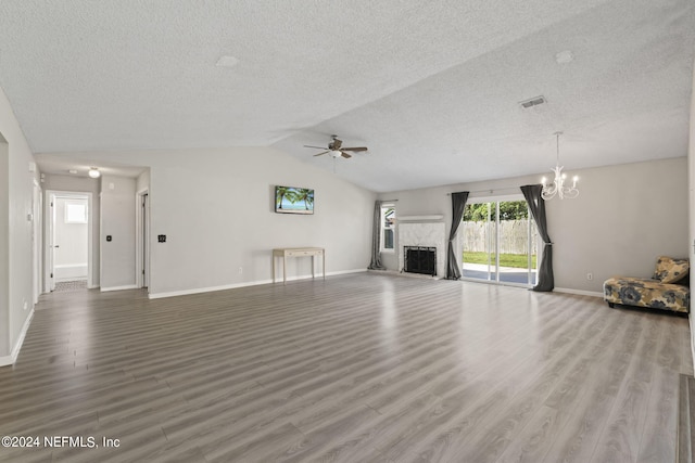 unfurnished living room with ceiling fan with notable chandelier, hardwood / wood-style flooring, lofted ceiling, and a textured ceiling