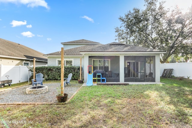 rear view of house featuring a yard, a fire pit, and a sunroom