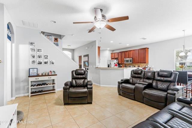 tiled living room featuring ceiling fan with notable chandelier and a textured ceiling