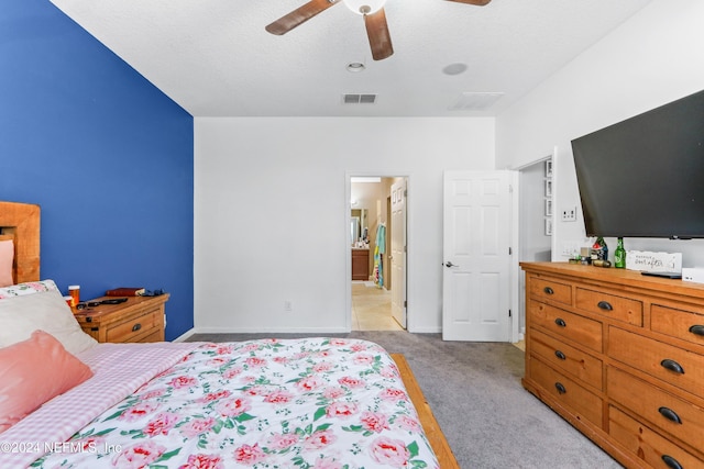 bedroom featuring light carpet, a textured ceiling, ceiling fan, and ensuite bathroom