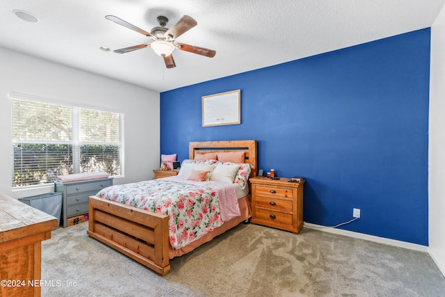 bedroom featuring ceiling fan, light carpet, and a textured ceiling