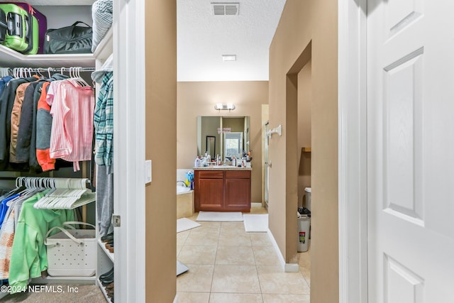 bathroom with tile patterned floors, a bathing tub, vanity, and a textured ceiling