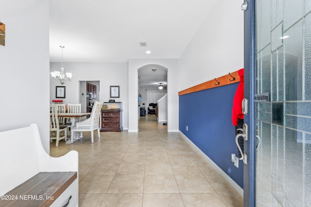 tiled foyer entrance with ceiling fan with notable chandelier