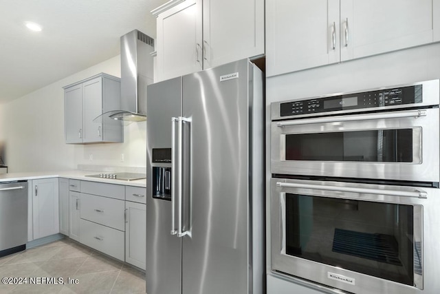 kitchen featuring appliances with stainless steel finishes, gray cabinetry, wall chimney exhaust hood, and light tile patterned flooring