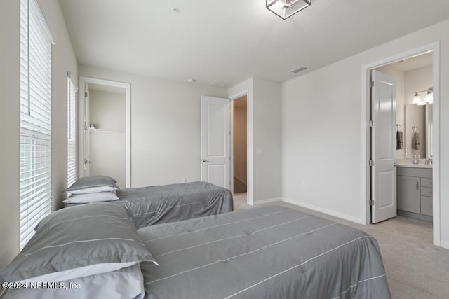 carpeted bedroom with ensuite bathroom and a closet