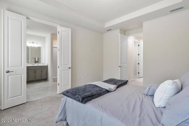 bedroom featuring light carpet and ensuite bath