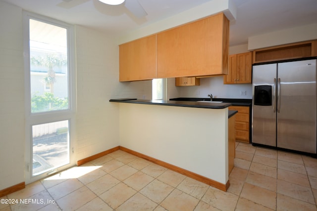 kitchen with stainless steel fridge with ice dispenser, sink, kitchen peninsula, light tile patterned floors, and ceiling fan