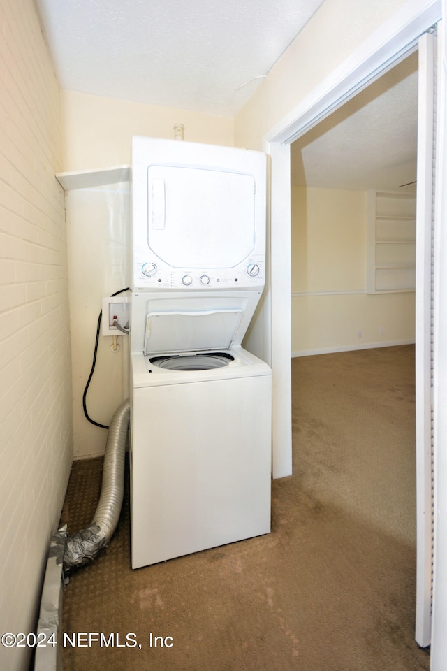 clothes washing area featuring carpet, brick wall, and stacked washer / dryer