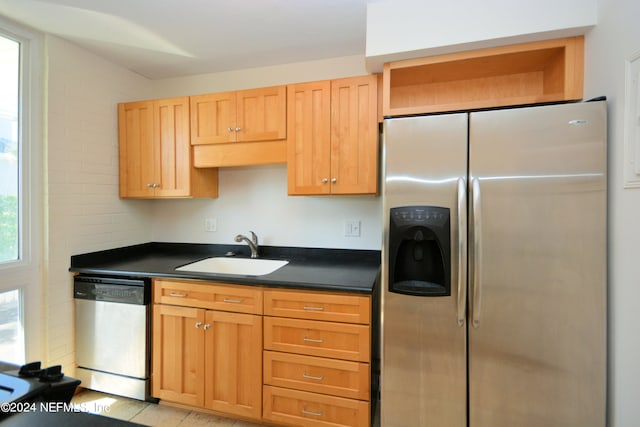 kitchen with appliances with stainless steel finishes, sink, and light hardwood / wood-style flooring