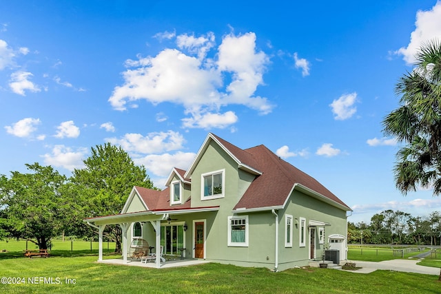 rear view of property featuring central AC unit, a patio, and a lawn