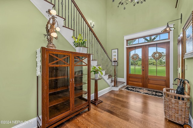 entrance foyer featuring a towering ceiling, french doors, and hardwood / wood-style flooring