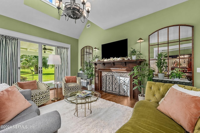 living room featuring lofted ceiling, a chandelier, hardwood / wood-style flooring, and a healthy amount of sunlight