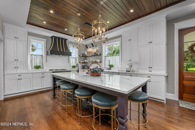 kitchen with white cabinets, wooden ceiling, a kitchen island, and dark hardwood / wood-style flooring