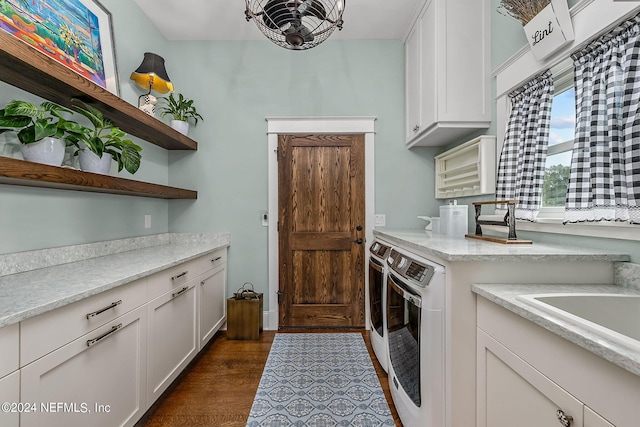 clothes washing area with dark wood-type flooring, washer and dryer, and cabinets