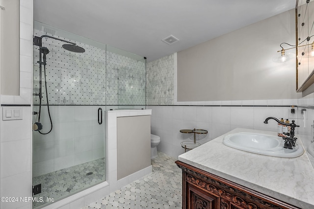 bathroom featuring vanity, tile walls, a shower with shower door, and toilet