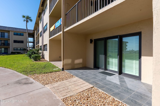 property entrance featuring a yard and a balcony