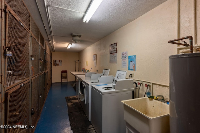 clothes washing area featuring sink, a textured ceiling, separate washer and dryer, and water heater