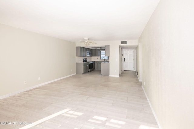 unfurnished living room featuring sink and ceiling fan