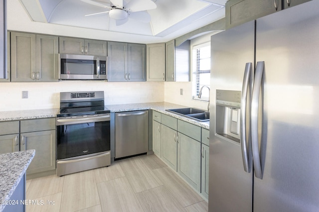 kitchen with sink, backsplash, ceiling fan, stainless steel appliances, and light stone counters