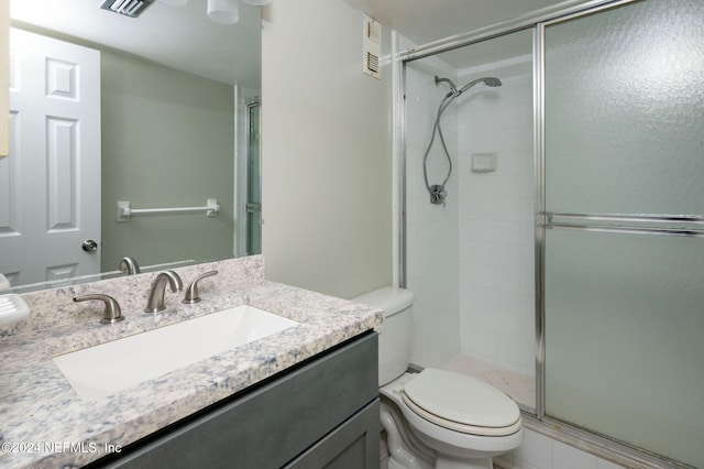 bathroom with vanity, toilet, and a shower with shower door