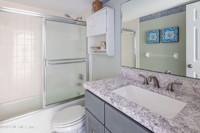 full bathroom with toilet, enclosed tub / shower combo, and vanity