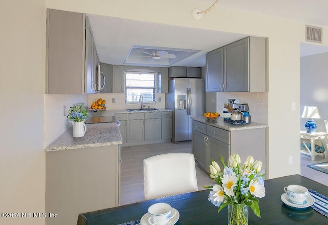 kitchen featuring sink, decorative backsplash, stainless steel fridge with ice dispenser, and gray cabinets