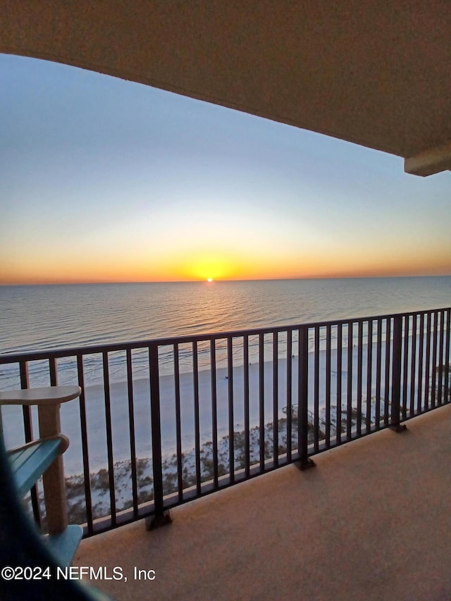 balcony at dusk with a view of the beach and a water view