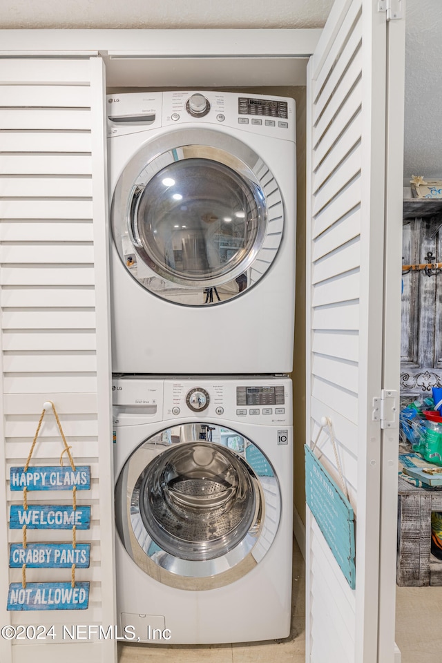 laundry room featuring a textured ceiling and stacked washer and dryer