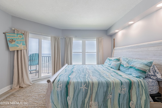 bedroom with wood-type flooring, a textured ceiling, and access to exterior