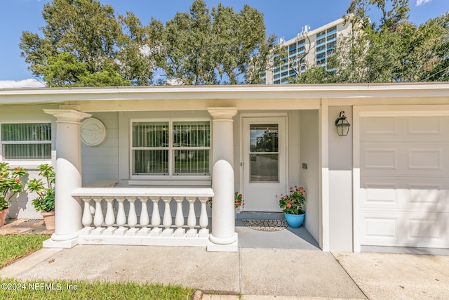 view of exterior entry featuring a garage and a porch