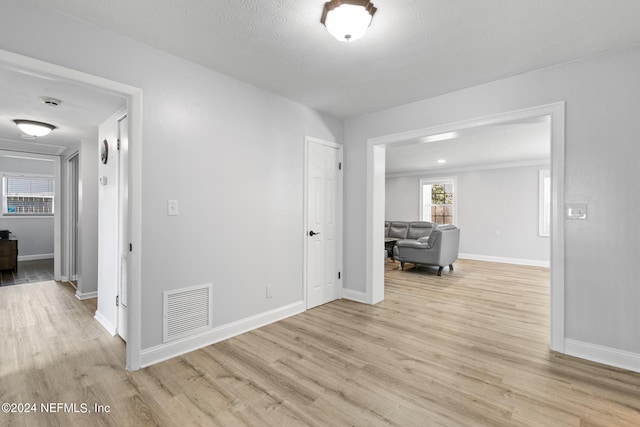 corridor with light wood-type flooring and a textured ceiling