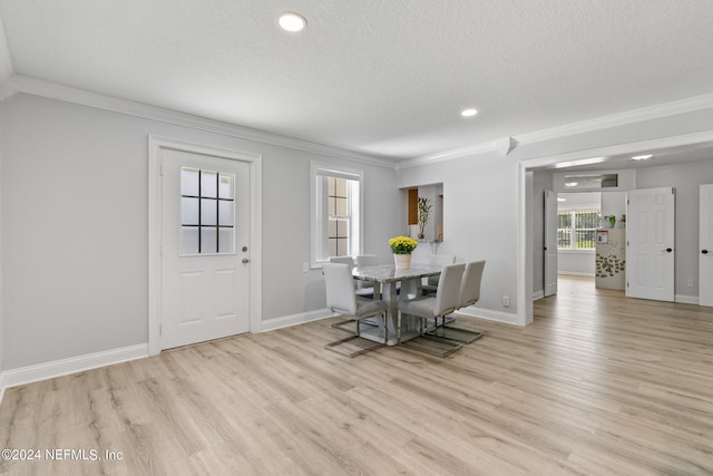 dining room with light hardwood / wood-style flooring, a textured ceiling, and crown molding