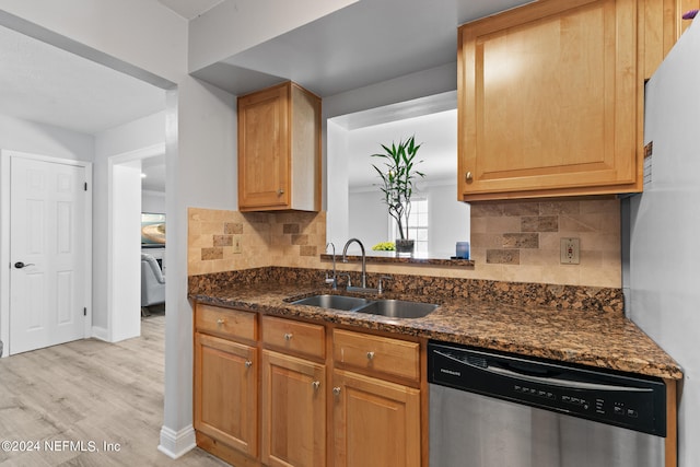 kitchen with sink, backsplash, dishwasher, dark stone counters, and light hardwood / wood-style floors