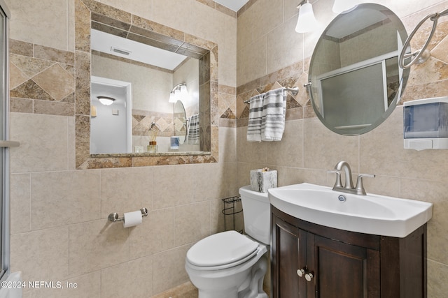 bathroom with vanity, tasteful backsplash, a shower with shower door, tile walls, and toilet