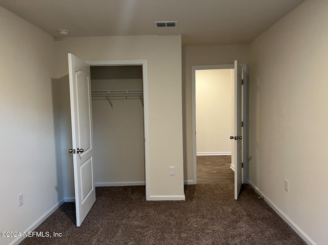 unfurnished bedroom featuring dark colored carpet and a closet