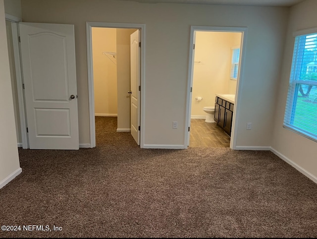 unfurnished bedroom with a closet, ensuite bath, carpet flooring, and a spacious closet