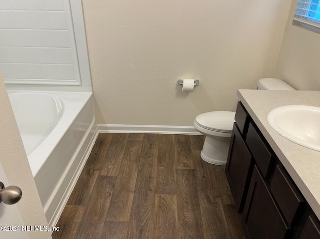 bathroom featuring vanity, wood-type flooring, a tub, and toilet